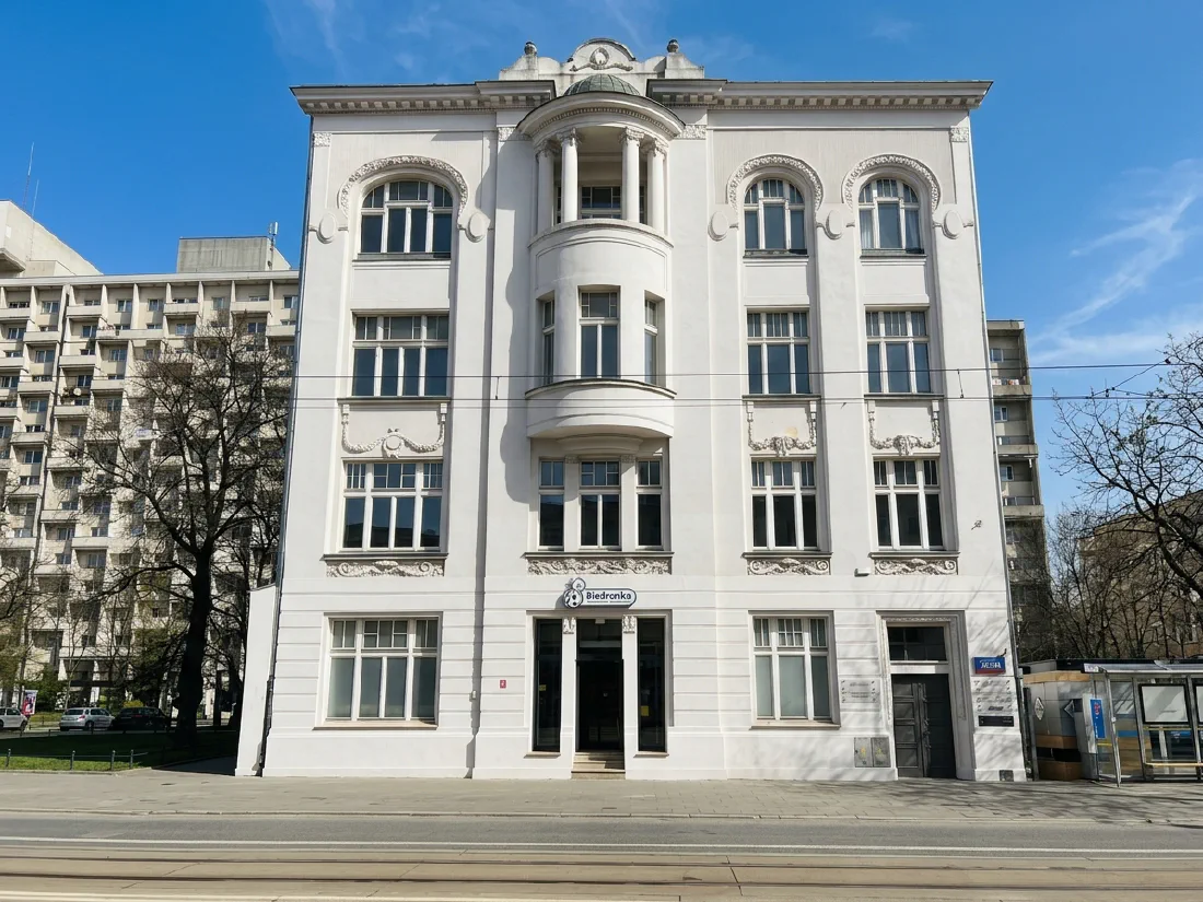 Front budynku przy ul. Piotrkowskiej 212/214 - biała kamienica, wejście od ulicy